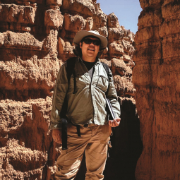 A male geoscientist, Daniel Ruiz Arriaga, stands in front of a rock formation